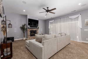 Carpeted living room with ceiling fan, a fireplace, baseboards, visible vents, and recessed lighting