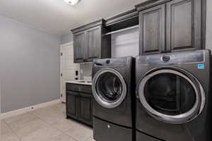 Washroom featuring separate washer and dryer, baseboards, light tile patterned flooring, and cabinet space