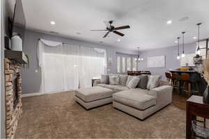 Living room featuring ceiling fan with notable chandelier, a fireplace, visible vents, and recessed lighting