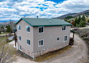 View of home's exterior with dirt driveway, roof with shingles, and a mountain view