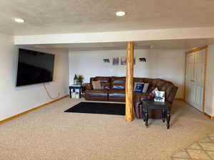 Carpeted living area featuring baseboards, a textured ceiling, and recessed lighting