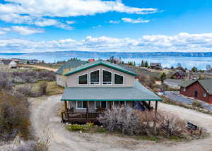 View of front of property with a porch, a water view, roof with shingles, and dirt driveway