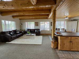 Living area with light colored carpet, beam ceiling, wood ceiling, and light tile patterned floors