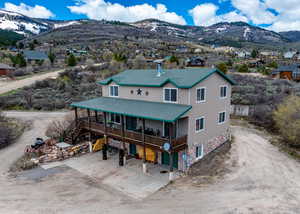 View of front of house with a shingled roof, a deck with mountain view, and driveway