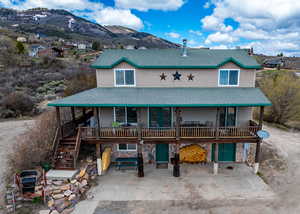 View of front of home featuring stone siding, roof with shingles, stairs, a patio area, and a mountain view