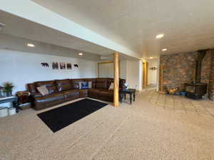 Carpeted living room with a wood stove, a textured ceiling, and recessed lighting