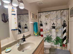 Bathroom featuring a shower with curtain, toilet, visible vents, tile patterned flooring, and vanity
