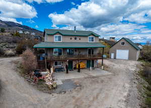 View of front of property featuring a garage, an outbuilding, a shingled roof, driveway, and stairway