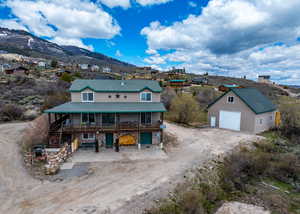 View of front facade with driveway, a garage, stairway, an outdoor structure, and a mountain view