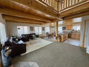 Living room with beamed ceiling, light carpet, and light tile patterned floors