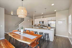 Dining area with stairway, dark wood finished floors, baseboards, and recessed lighting