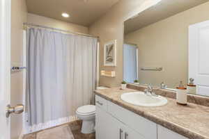 Bathroom featuring tile patterned flooring, toilet, vanity, and recessed lighting