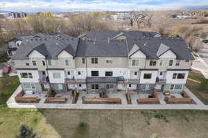 Rear view of property with stone siding, a patio area, a shingled roof, and a residential view
