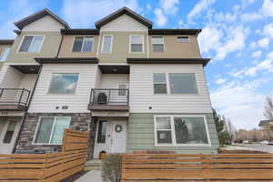 Multi unit property featuring fence, a balcony, and stone siding