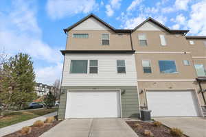 Townhome / multi-family property with an attached garage, driveway, and central AC unit