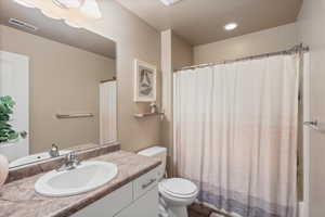 Bathroom featuring shower / bath combo, toilet, vanity, and visible vents