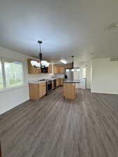 Kitchen featuring dark wood-style flooring, open floor plan, visible vents, an inviting chandelier, and black appliances