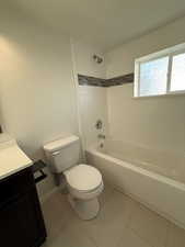 Bathroom featuring washtub / shower combination, toilet, vanity, and tile patterned floors