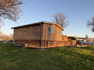 Rear view of property with a lawn and cooling unit