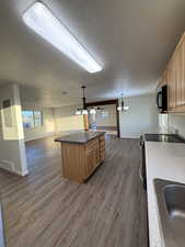 Kitchen featuring open floor plan, a textured ceiling, stainless steel range with electric stovetop, and black microwave