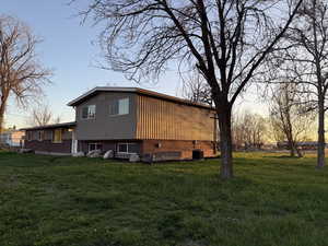Property exterior at dusk with board and batten siding, a lawn, and central AC unit