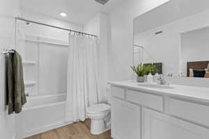 Bathroom featuring wood finished floors, visible vents, toilet, vanity, and shower / tub combo with curtain