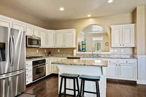 Kitchen with recessed lighting, a sink, a kitchen island, a kitchen bar, and appliances with stainless steel finishes
