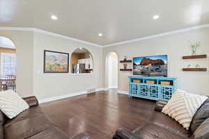 Living room featuring arched walkways, baseboards, visible vents, recessed lighting, and wood finished floors