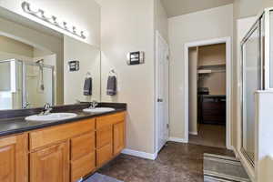 Full bath featuring a sink, double vanity, and a stall shower
