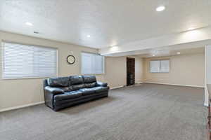 Carpeted living area with recessed lighting, a textured ceiling, and baseboards