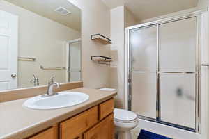 Full bath featuring vanity, visible vents, a shower stall, and toilet