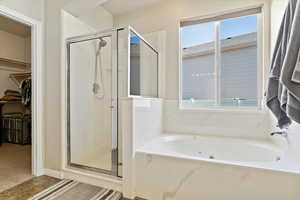 Bathroom with a walk in closet, a garden tub, and a stall shower