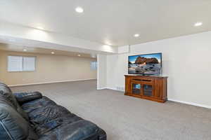 Carpeted living room featuring baseboards, visible vents, and recessed lighting