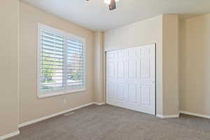Unfurnished bedroom featuring visible vents, carpet flooring, and multiple windows