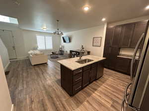 Kitchen with dark brown cabinets, wood finished floors, a sink, and appliances with stainless steel finishes