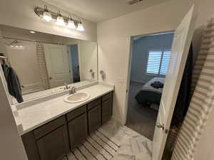Ensuite bathroom with a shower with curtain, ensuite bathroom, baseboards, marble finish floor, and vanity