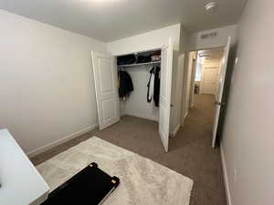 Unfurnished bedroom with baseboards, visible vents, carpet, and a closet