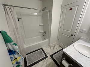 Bathroom featuring baseboards, vanity, marble finish floor, and shower / bathtub combination with curtain