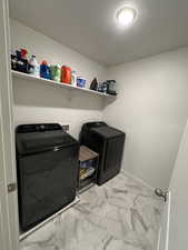 Laundry room with marble finish floor, washer and clothes dryer, and laundry area