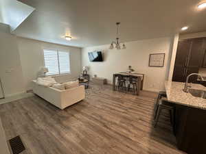 Living area featuring recessed lighting, dark wood-style floors, an inviting chandelier, visible vents, and baseboards