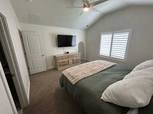 Carpeted bedroom featuring vaulted ceiling, visible vents, baseboards, and ceiling fan