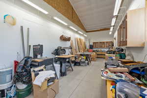 Interior space featuring concrete flooring, lofted ceiling, and a workshop area