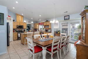 Dining area with visible vents, a toaster, a chandelier, and light tile patterned floors