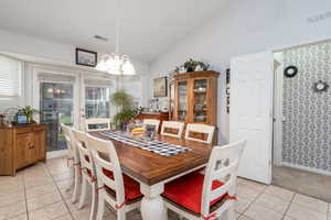 Dining room featuring high vaulted ceiling, a notable chandelier, visible vents, and light tile patterned floors