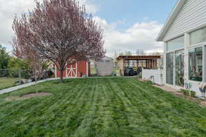 View of yard featuring a storage shed, an outbuilding, a pergola, and fence