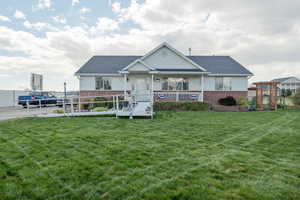 View of front of home with brick siding, a shingled roof, a front yard, and fence