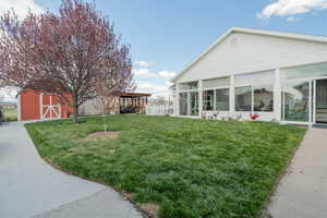 View of yard featuring a sunroom, an outbuilding, a storage unit, and a pergola