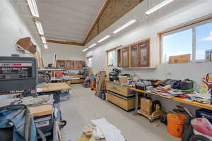 Miscellaneous room with concrete floors, a workshop area, and high vaulted ceiling
