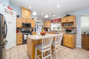 Kitchen with backsplash, appliances with stainless steel finishes, and light brown cabinets