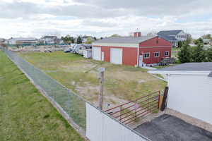 View of yard featuring fence, an outbuilding, a pole building, and a garage